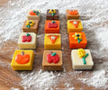 Square dog truffles in white, tan, brown, orange, and yellow topped with pumpkins, apples, flowers, and pie-slice decorations.